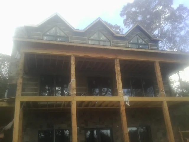 Dormers and porch framing on a large log home under construction — Roof Coating work by our crew in Eaton