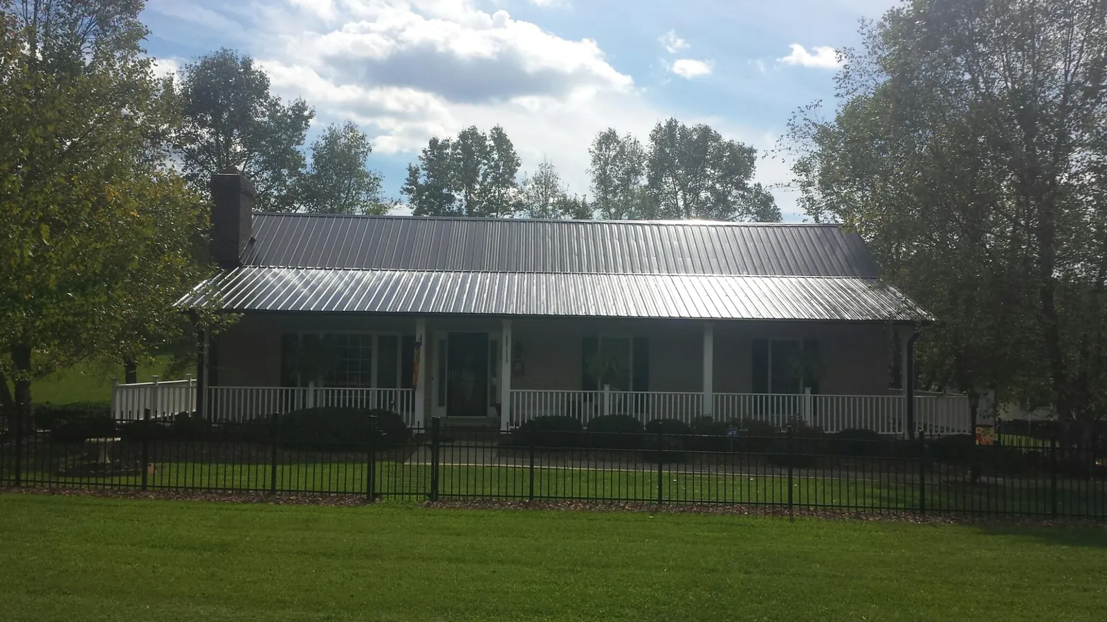 Gray metal roof on a brick ranch with a full width front porch — Gutter Guard Installation work by our crew in Eaton